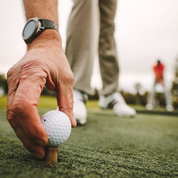 hand placing golf ball on tee